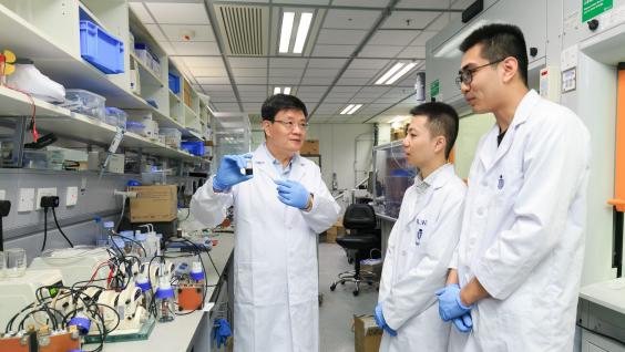 Prof. Zhao Tianshou (left) shows a sample of the e-fuel to his team members.