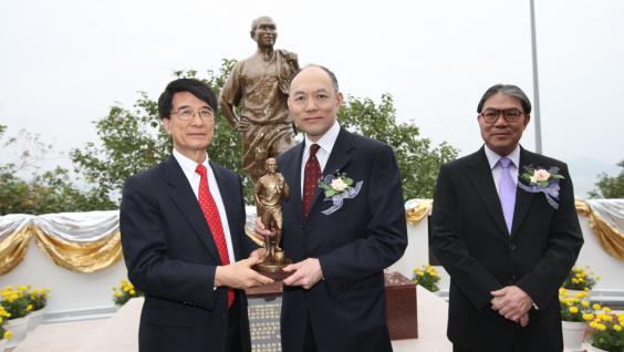 朱 經 武 校 長 (左) 致 送 小 型 銅 像 紀 念 品 給 霍 震 寰 先 生 ； 旁 為 霍 震 霆 先 生	